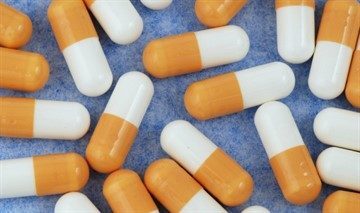 yellow-and-white-medical-capsules-isolated-on-the-blue-background